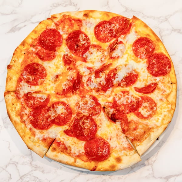 A whole pepperoni pizza with melted cheese and a golden crust, sliced on a marble surface.